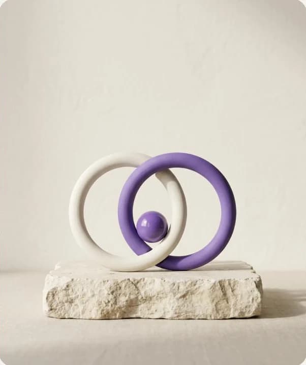 Twee ineengrijpende ringen, wit en violet, op een stenen sokkel