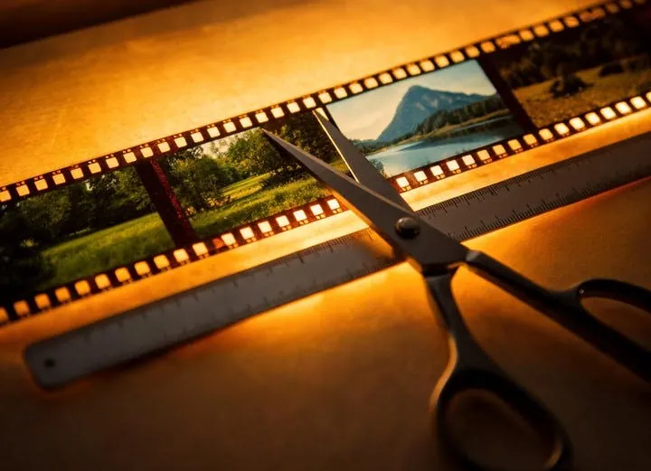 Editor's scissors resting at a natural scene-change point on a measured filmstrip, representing Seedance 2.5's Smart Duration feature.